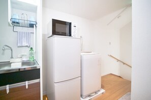 A compact kitchen with a refrigerator, microwave, sink, and a small countertop.