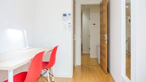 Ein modernes Zimmer mit Schreibtisch, Stühlen und einer Tür zu einem weiteren Raum.