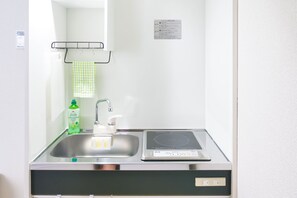 A bathroom with a sink, a mirror, a towel rack, and a bottle of liquid soap.