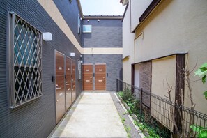 A narrow alleyway with a concrete path, metal fences, and wooden doors.