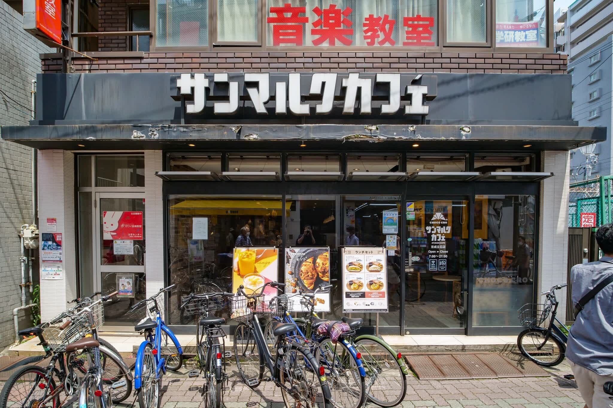 A storefront with a sign in Japanese characters, bicycles parked outside, and a person in the background.