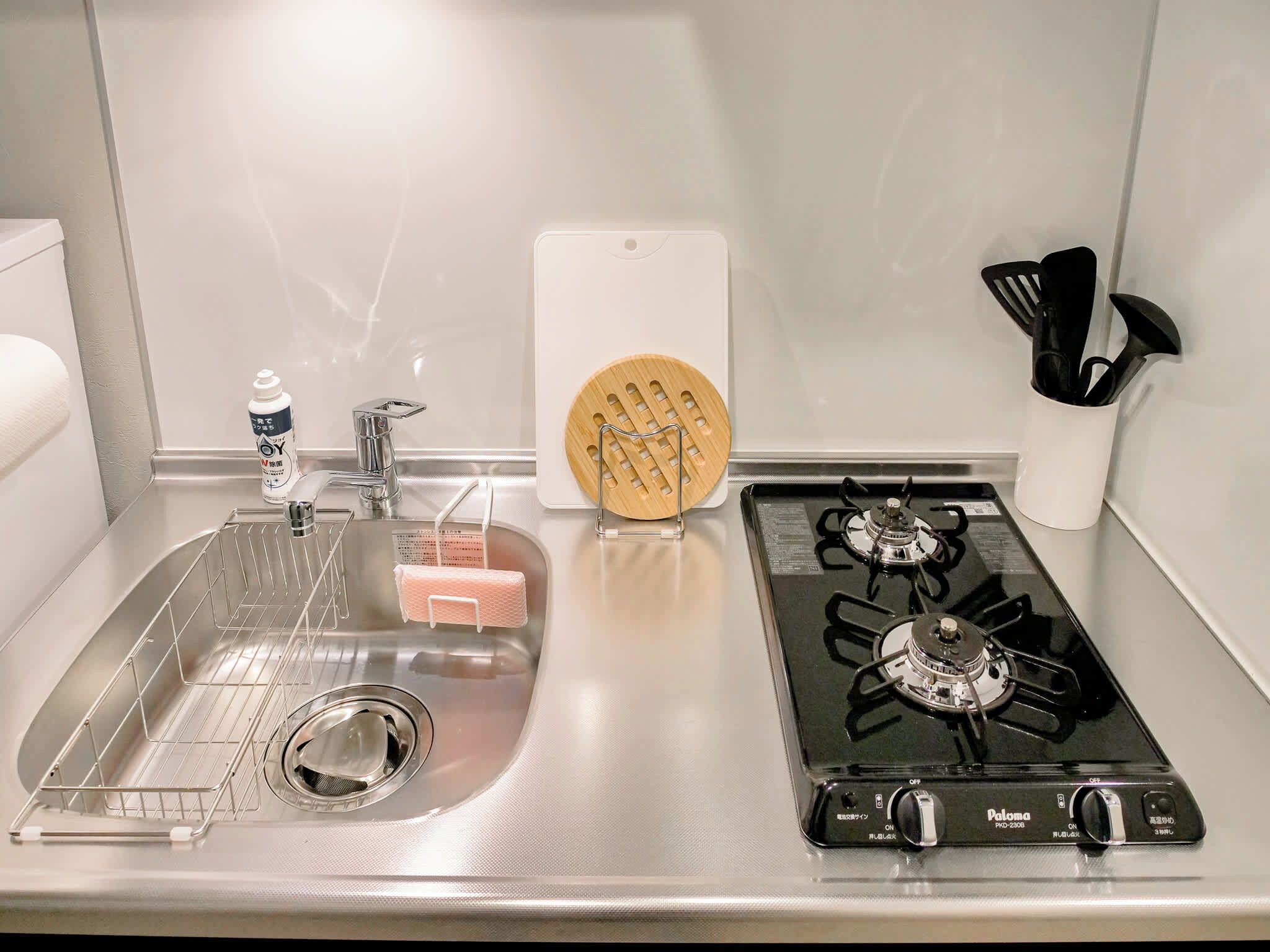 Une cuisine équipée d’un évier en acier inoxydable, d’une planche à découper en bois et d’une cuisinière à gaz.