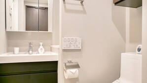 Uma casa de banho moderna com uma pia branca, um espelho, uma sanita e um porta-toalhas.