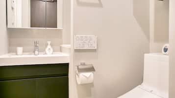 A modern bathroom with a white sink, a mirror, a toilet, and a towel rack.