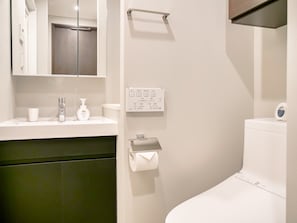Un baño moderno con un lavamanos blanco, un espejo, un inodoro y un perchero para toallas.