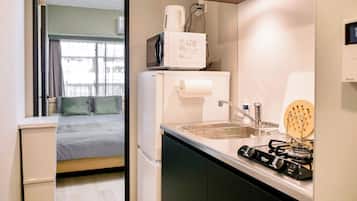 A compact kitchenette with a microwave, refrigerator, sink, and gas stove.