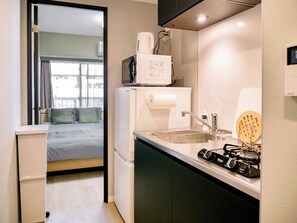 Una kitchenette compacta con microondas, refrigerador, pileta y estufa a gas.