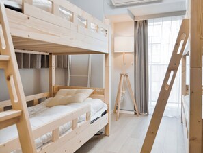Dormitori amb lliteres, una escala de fusta, una làmpada de peu i una finestra amb cortines.