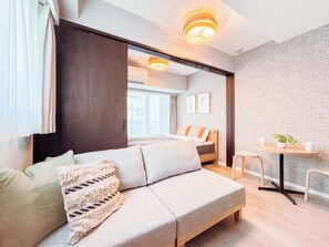 Ein modernes Hotelzimmer mit einer Sitzecke, einem kleinen Tisch und Blick auf die Stadt.