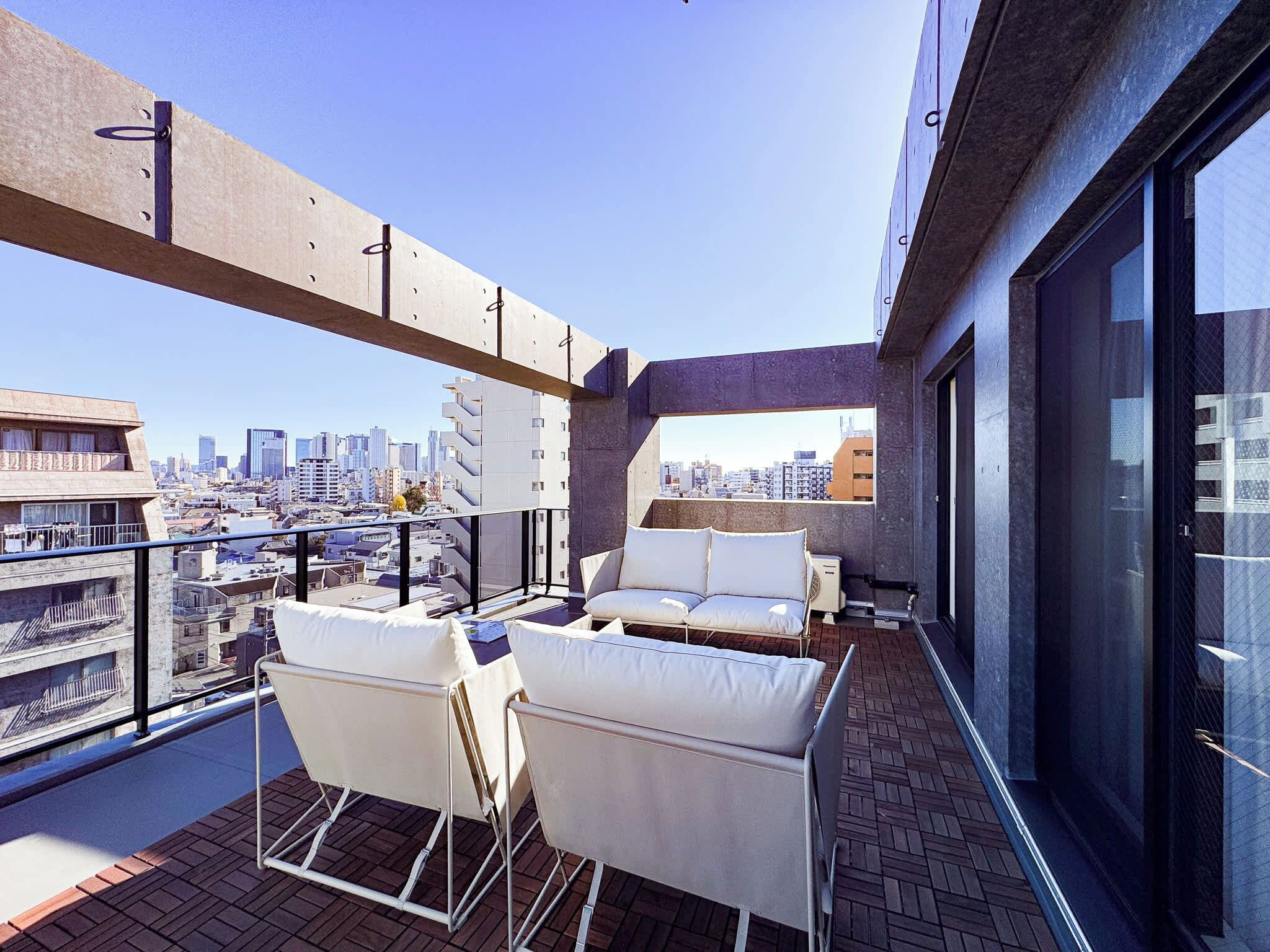 Eine Dachterrasse mit Blick auf die Stadt, einem Sofa und einem Sessel.