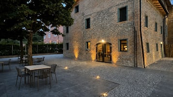 Un bâtiment en pierre doté d’un patio, d’un espace extérieur aménagé avec des sièges et d’un arbre.