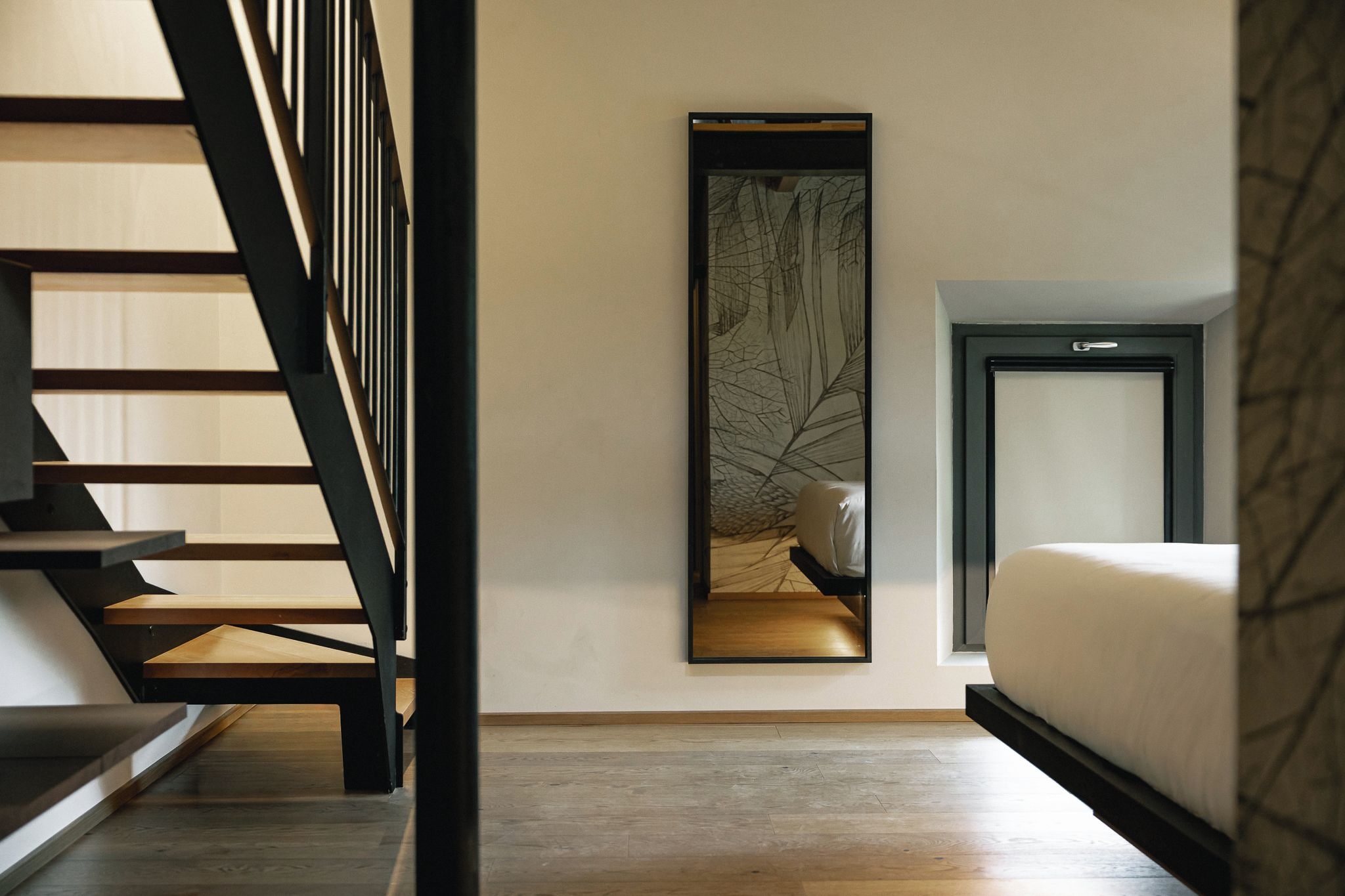 Un dormitorio moderno con una cama, un espejo grande y una escalera.