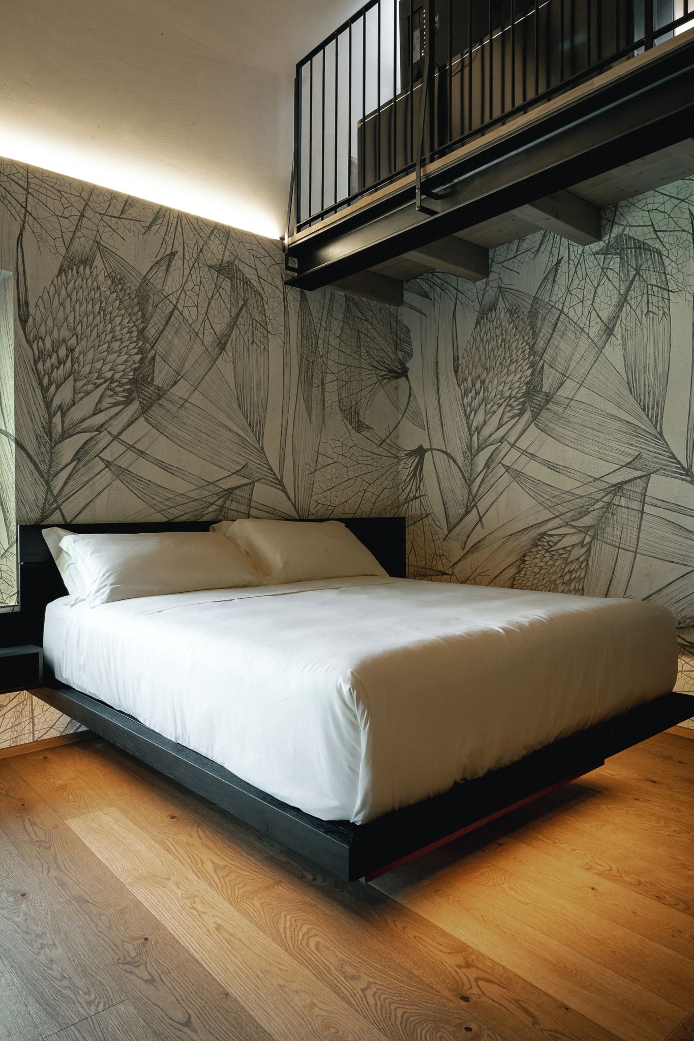 A modern bedroom with a bed, wooden flooring, and a unique wall design.