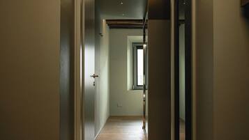 A narrow hallway with wooden flooring and a door at the end.