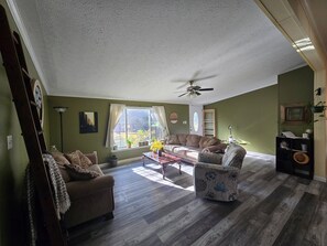 A spacious living room with a ceiling fan, a sofa, a chair, and a coffee table.