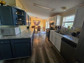 A kitchen with a central island, built-in appliances, and a dining area with a chandelier.