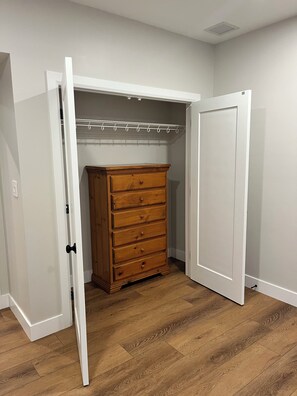 Una habitación con un aparador de madera, un armario blanco con barra y una puerta blanca.