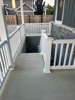 A wooden deck with white railings leading to a covered area.