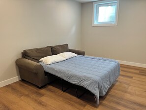 Ein gemütlicher Raum mit Bett, Schlafsofa und Fenster.