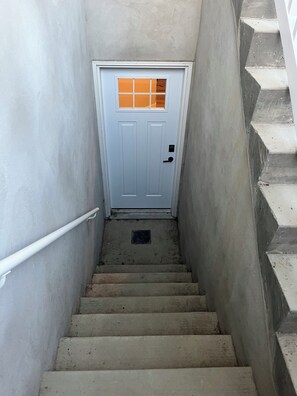 A concrete staircase leading to a white door with a small window.