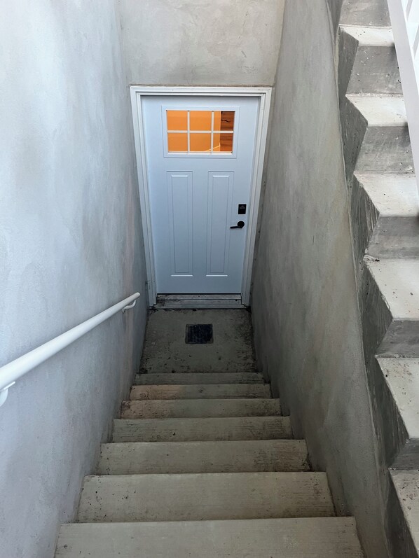 A concrete staircase leading to a white door with a small window.