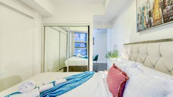 Ein Hotelzimmer mit einem Bett, einem Nachttisch, einem Sessel, einer Topfpflanze und Blick auf die Stadt.