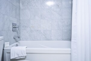 Een moderne badkamer met een badkuip, toilet en douchegordijn.