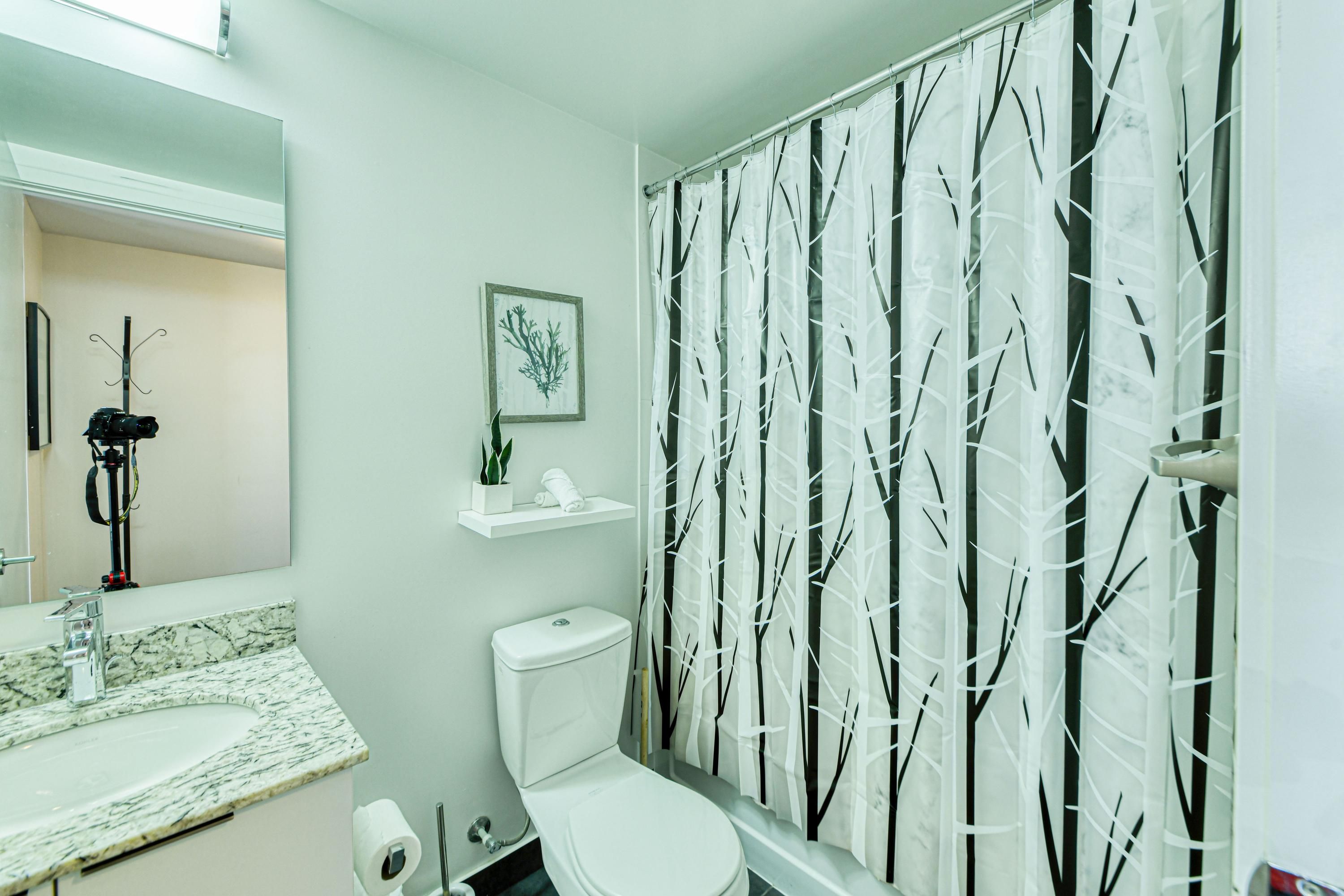 Een badkamer met toilet, wastafel en douchegordijn met een boommotief.