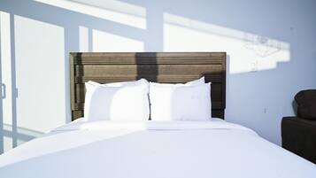 Una cama bien tendida con sábanas blancas y un cabecero de madera en una habitación de hotel.