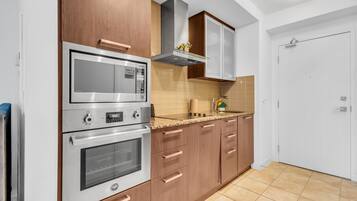 Eine moderne Küche mit Edelstahlgeräten, Holzschränken und einer gefliesten Spritzschutzleiste.