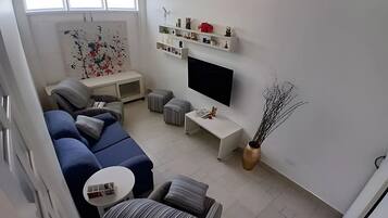 Una sala de estar moderna con un sofá modular, un televisor de pantalla plana y estanterías empotradas.