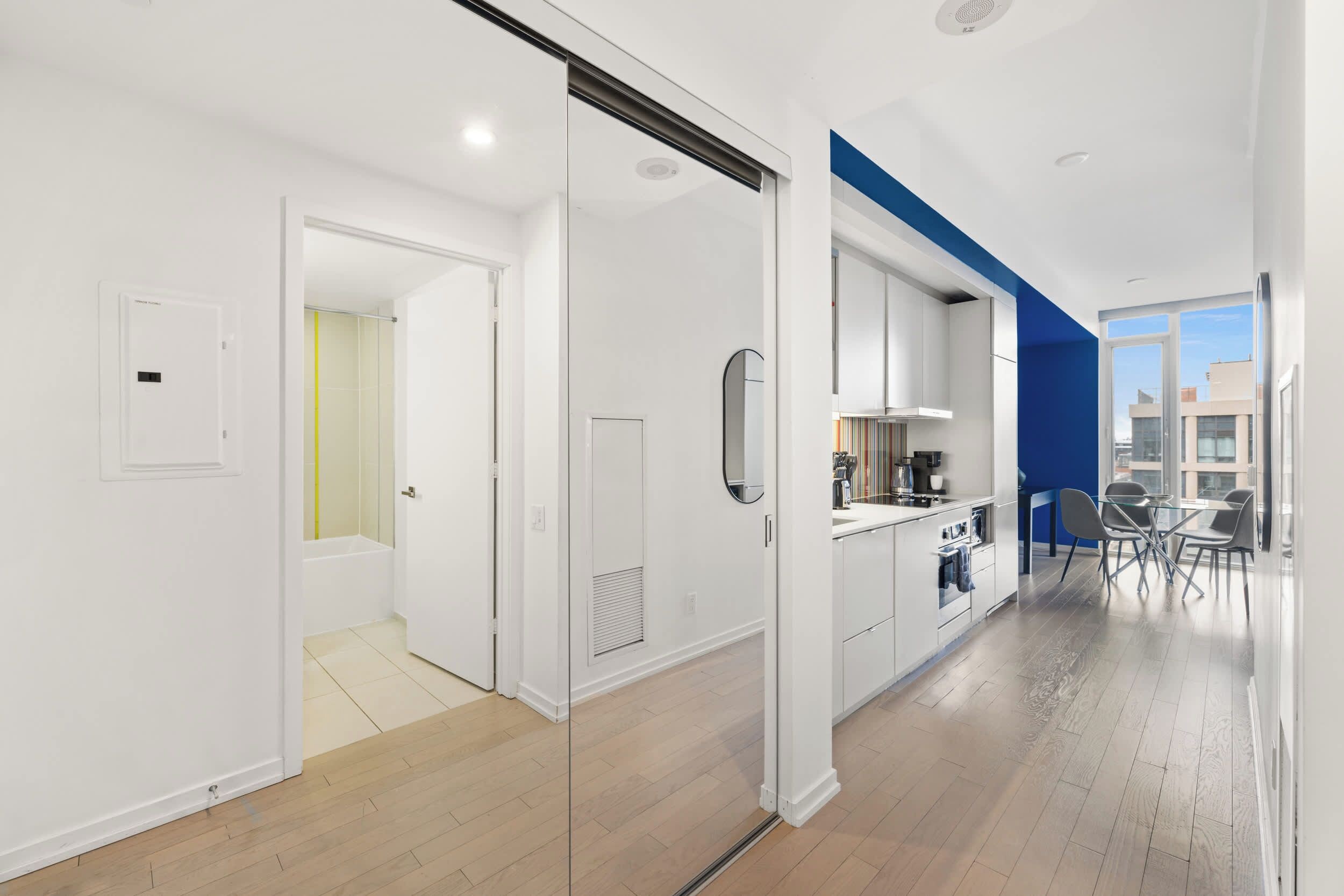 A modern apartment with a kitchen, dining area, and a bathroom with a shower.