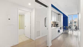 A modern apartment with a kitchen, dining area, and a bathroom with a shower.