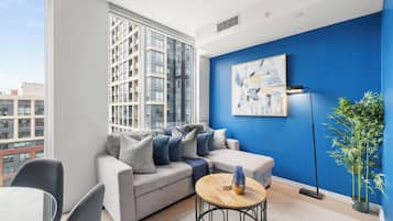 A modern living room with a grey sofa, a round wooden coffee table, and a blue accent wall.