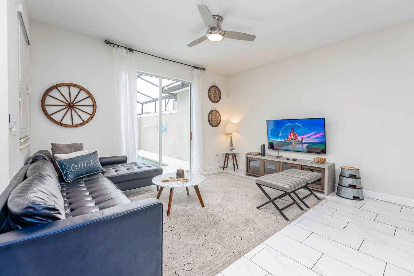 A modern living room with a sofa, a coffee table, a TV, and a ceiling fan.
