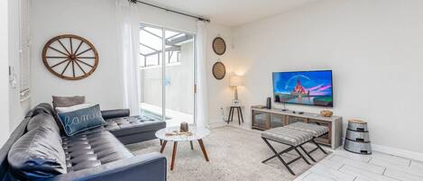 A modern living room with a sofa, a coffee table, a TV, and a ceiling fan.