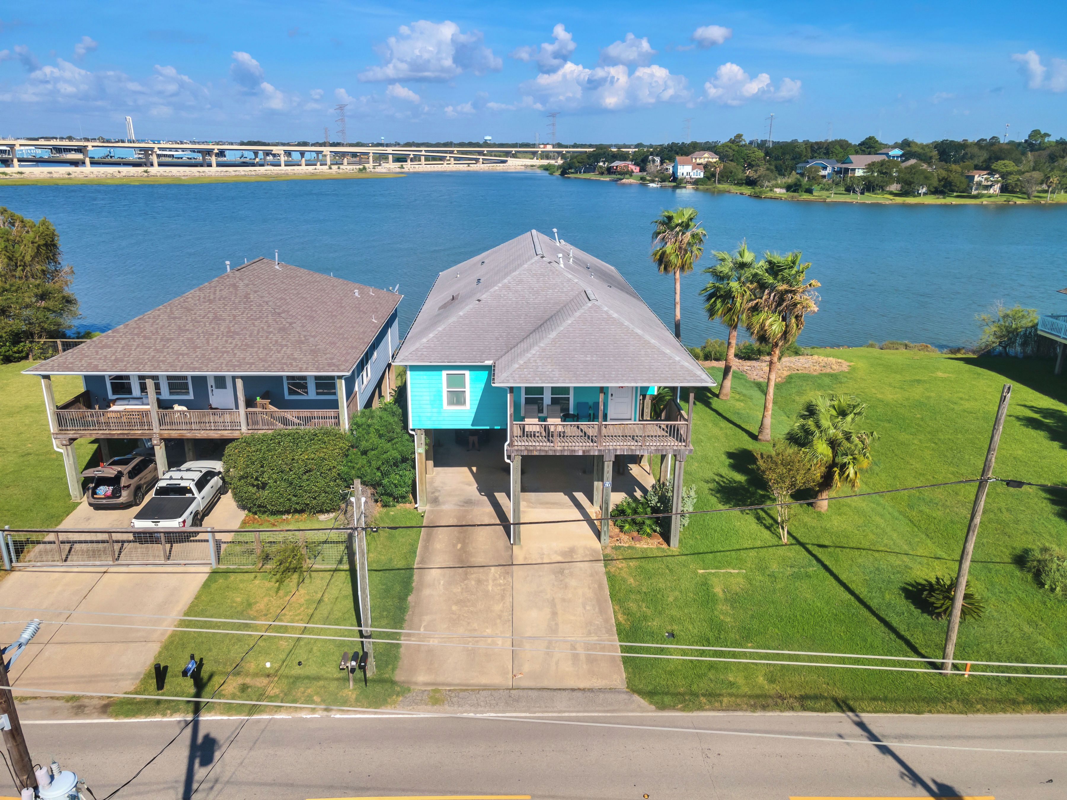 A residential area with two houses, a dock, and a bridge in the background.