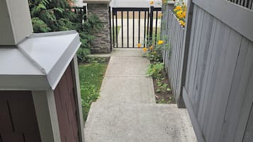 A concrete pathway leading to a gated area with a stone wall and a wooden fence.