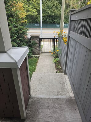 A concrete pathway leading to a gated area with a stone wall and a wooden fence.