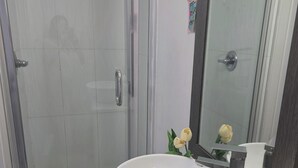 Une salle de bain avec une douche à parois de verre, un lavabo blanc et un miroir au-dessus.