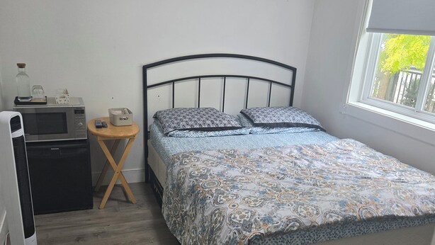 Une chambre à coucher avec un lit, une horloge murale, une table de chevet avec une lampe et une fenêtre.