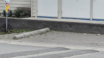 A building with a garage door, a sign indicating authorized parking, and a warning sign for high voltage.