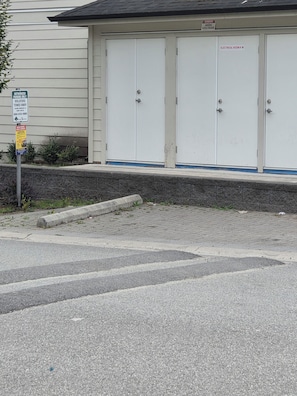 A building with a garage door, a sign indicating authorized parking, and a warning sign for high voltage.
