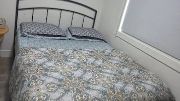 A bedroom with a bed, a wall clock, and a window.