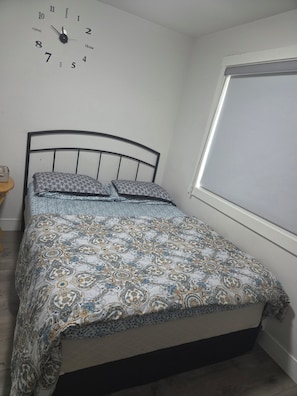 A bedroom with a bed, a wall clock, and a window. - Serene 1-bedroom townhome in welcoming Surrey neighborhood (Surrey)