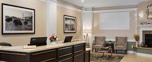 A reception area with a desk, chairs, framed pictures, and a fireplace. - Celebrate NYE in San Francisco — Luxury 1BR Hotel Suite (San Francisco)