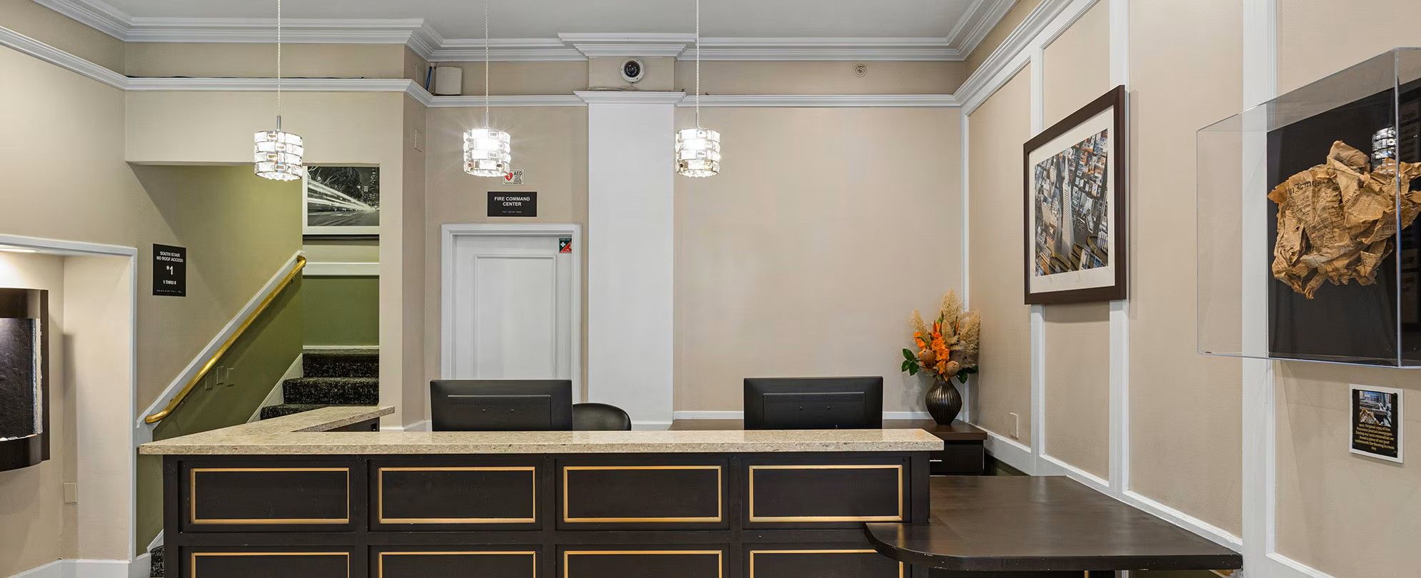 A reception area with a counter, chairs, a fire command center sign, a staircase, and a framed picture on the wall.
