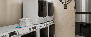 A laundry area with stacked towels, a Maytag dryer, and a stainless steel refrigerator.