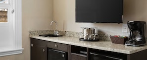 A kitchen with a granite countertop, a coffee maker, and a wine glass holder.