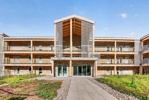 Ein mehrstöckiges Gebäude mit einem zentralen Atrium, Balkonen und einem begrünten Innenhof.